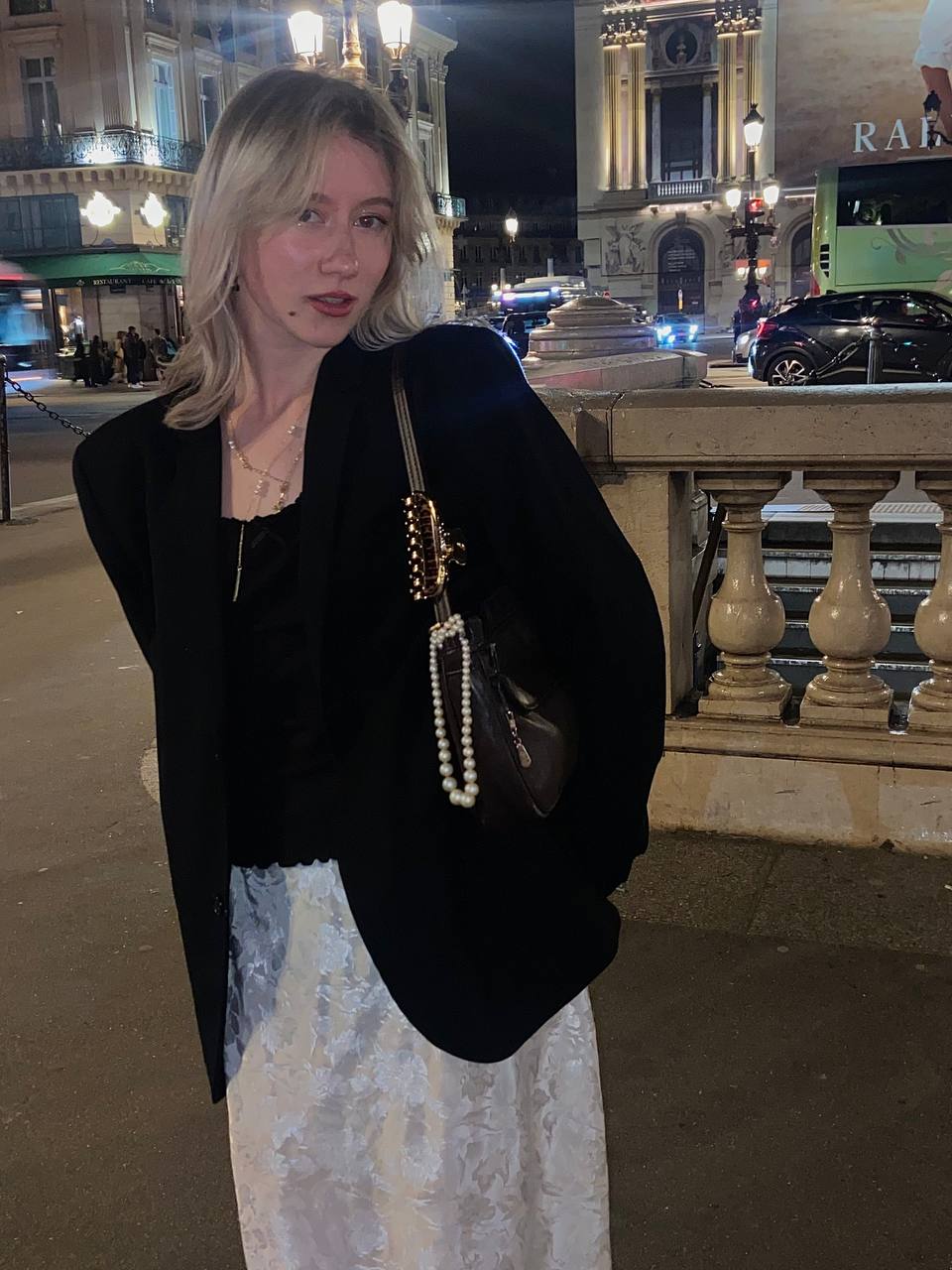 Фото девушки в белой юбке и черном пиджаке. Из аксессуаров – черная кожаная сумка с жемчужной подвеской.